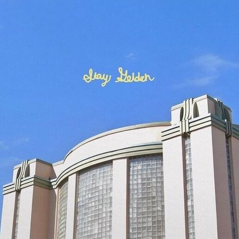 Text: "Stay Golden". Gebäude mit Art-Deco-Architektur und bunter Schallplatte mit Farbspritzern.