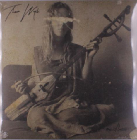 Oben steht „The Witch“. Eine Frau sitzt und hält ein Streichinstrument. Das Bild ist in Sepia gehalten.