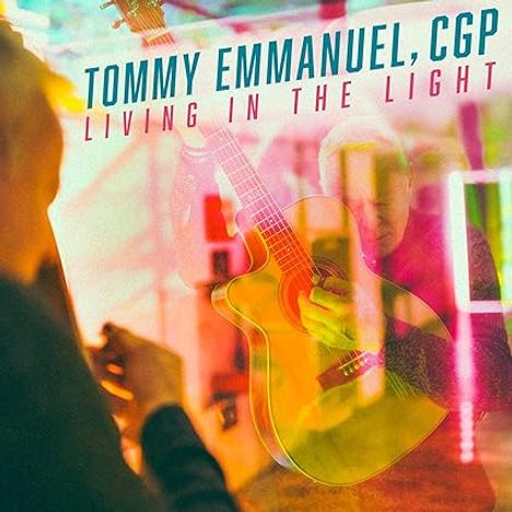 "TOMMY EMMANUEL, CGP - LIVING IN THE LIGHT" in bunten Buchstaben über einem Mann mit Akustikgitarre.