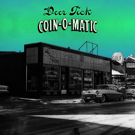 "Deer Tick COIN-O-MATIC" in großen Buchstaben oben. Ein altes Auto steht vor einem kleinen Geschäft auf verschneitem Boden.