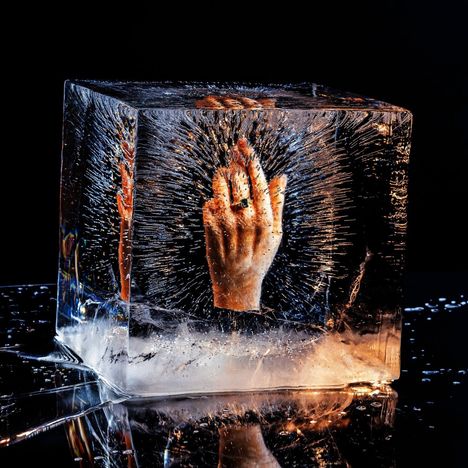 Kein Text sichtbar. Eine Hand mit Ring ist in einem klaren Eisblock eingeschlossen, umgeben von Luftblasen.