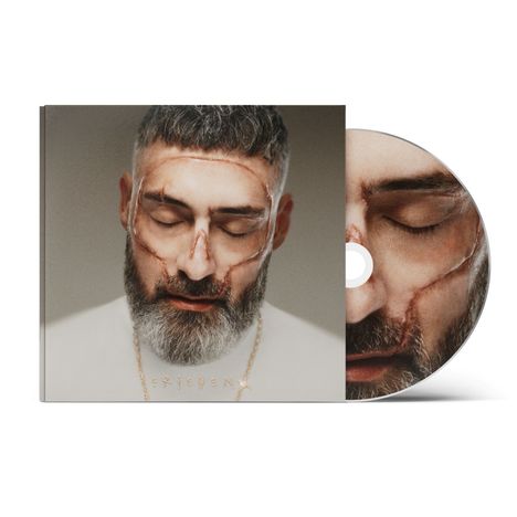 „FRIEDEN“ in goldenen Buchstaben. Ein Mann mit geschlossenen Augen und Narben auf dem Gesicht, daneben eine CD mit demselben Bild.