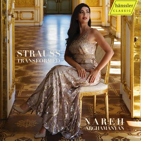 „STRAUSS TRANSFORMED“, „NAREH ARGHAMANYAN“. Eine Frau in einem goldenen Raum sitzt elegant auf einem Stuhl.