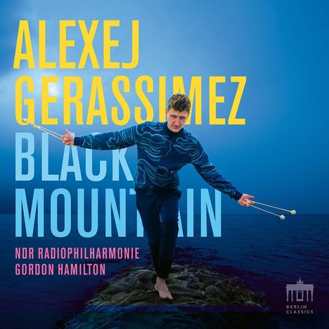 „Alexej Gerassimez, Black Mountain, NDR Radiophilharmonie, Gordon Hamilton.“ Ein Mann balanciert mit Schlegeln am Meer.
