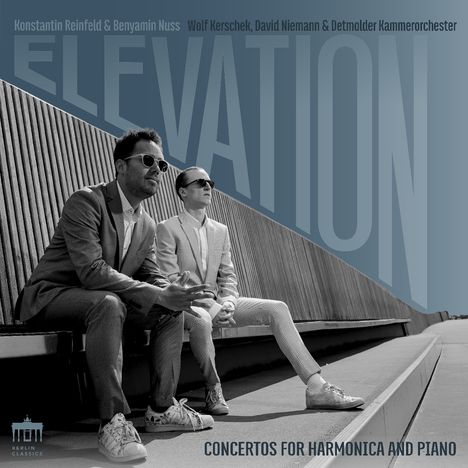 Text: "Konstantin Reinfeld & Benyamin Nuss. ELEVATION. Concertos for Harmonica and Piano." Zwei Männer in Anzügen sitzen auf einer Bank.