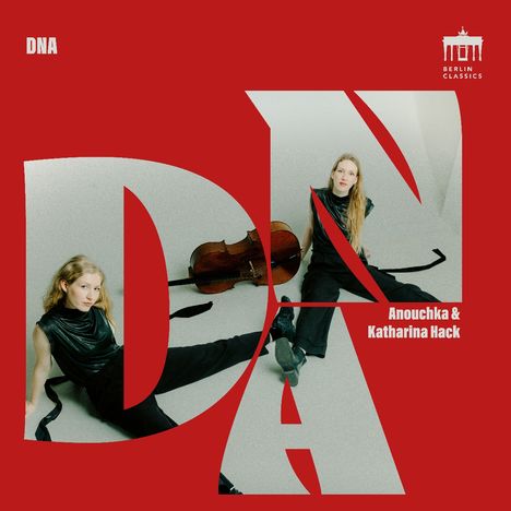 DNA. Anouchka & Katharina Hack. Zwei Frauen in schwarzer Kleidung mit Cello vor rotem Hintergrund.