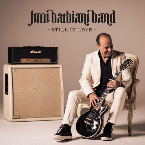 Text: "Jimi Barbiani Band - Still in Love." Ein Mann im hellen Anzug hält eine Gitarre, neben ihm steht ein Verstärker.