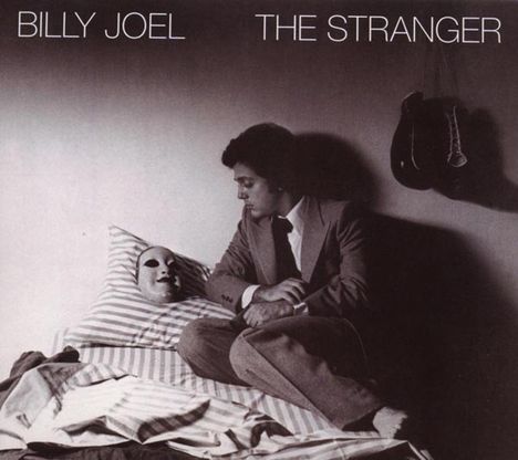 "BILLY JOEL THE STRANGER" steht oben. Ein Mann im Anzug sitzt auf einem Bett, starrt eine Maske auf dem Kissen an.