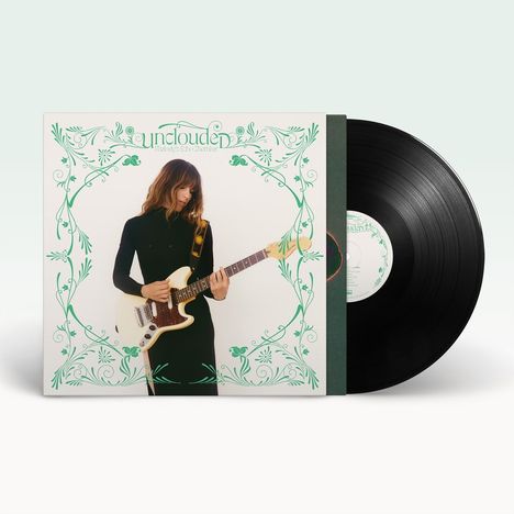 "Unclouded", Melody's Echo Chamber. Eine Frau in Schwarz spielt E-Gitarre, umgeben von grünen Verzierungen. Vinyl.
