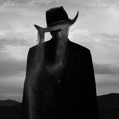 "DEVON GILFILLIAN" und "TIME WILL TELL" oben. Silhouette eines Mannes im Anzug mit Cowboyhut, aus dem Sand fließt. Schwarz-weiß.