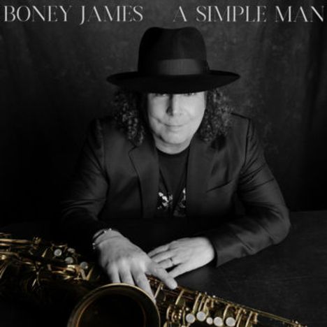 Text: "Boney James A Simple Man." Ein Mann mit Hut und Locken sitzt hinter einem Saxophon. Schwarz-weißes Bild.