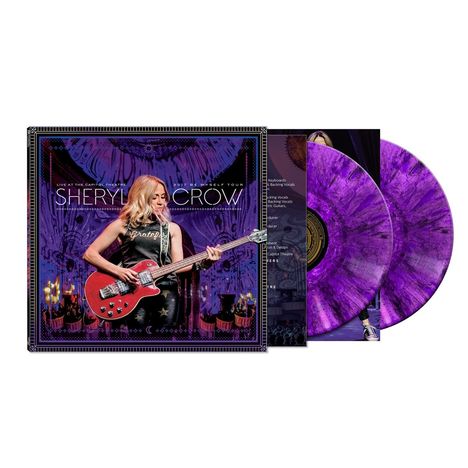 "Sheryl Crow" und "LIVE AT THE CAPITOL THEATRE" in großen Buchstaben. Frau mit Gitarre auf Albumcover, violette Schallplatten.
