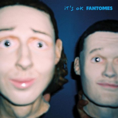 Text "it's ok FANTOMES" oben rechts. Verschwommene Gesichter zweier Puppen mit ausdruckslosen, großen Augen.