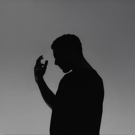 Ein silhouettierter Mann im Profil hebt seine Hand gegen einen grauen Hintergrund.