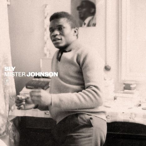 Der Text lautet "SLY MISTER JOHNSON". Ein Mann steht in einem Raum und hält etwas, hinter ihm ist ein Spiegel.