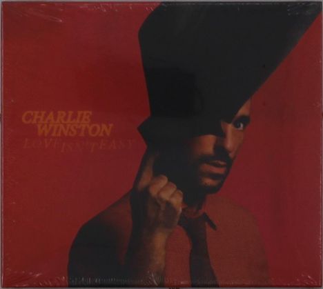 "CHARLIE WINSTON, LOVE ISN'T EASY", ein ernst blickender Mann mit Zylinder auf rotem Hintergrund.