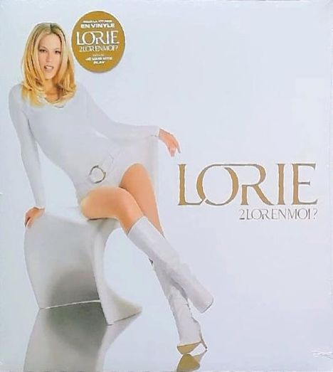 „LORIE 2Lorenmoi?“ Frau in weißem Kleid und Stiefeln sitzt auf einem modernen Stuhl. Goldener Kreis oben links.