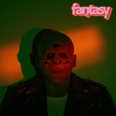 Text: „fantasy“ in neonfarben. Ein Mensch mit mehreren Augen und surrealem Gesichtsausdruck vor farbigem Hintergrund.