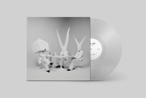 Ein Albumcover zeigt drei Personen mit großen, abstrakten Papierhüten an einem Tisch. Rechts daneben liegt eine Schallplatte.