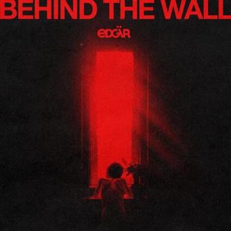 Text: "BEHIND THE WALL", "EDGAR". Eine Person vor einem roten, leuchtenden Fenster in dunkler Umgebung.