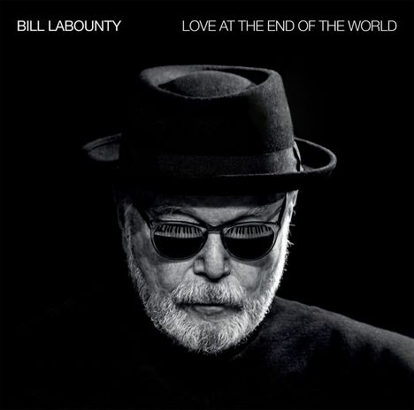 Oben zwei Texte: "BILL LABOUNTY" und "LOVE AT THE END OF THE WORLD". Ein Mann mit Hut, Bart, Sonnenbrille, schwarz-weiß gehalten.