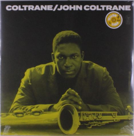 Text: "COLTRANE/JOHN COLTRANE". Eine ernst blickende Person lehnt sich über ein Saxophon. Gelb getöntes Cover.
