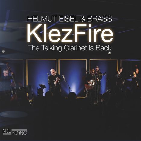 "HELMEUT EISEL & BRASS KlezFire: The Talking Clarinet Is Back." Eine Band spielt auf einer Bühne, bläuliche Beleuchtung.