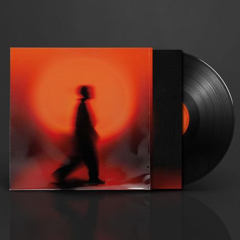 Vorne eine Silhouette vor orange-rotem Licht, rechts eine Vinyl-Schallplatte teilweise sichtbar.