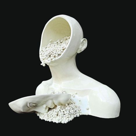 Eine weiße Skulptur eines kopflosen Menschen, dessen Gesicht und Oberkörper mit kleinen Kugeln gefüllt sind.