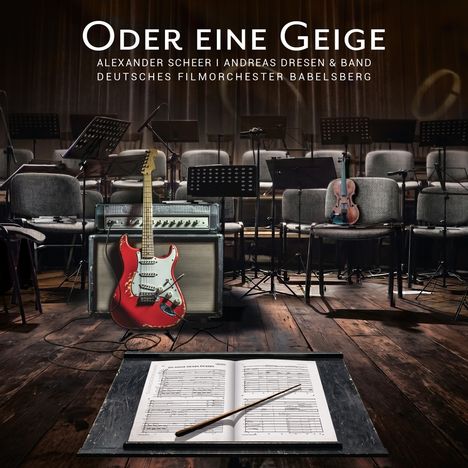 Im Vordergrund Notenpult mit Partitur, daneben rote E-Gitarre, im Hintergrund eine Geige auf einem Stuhl.