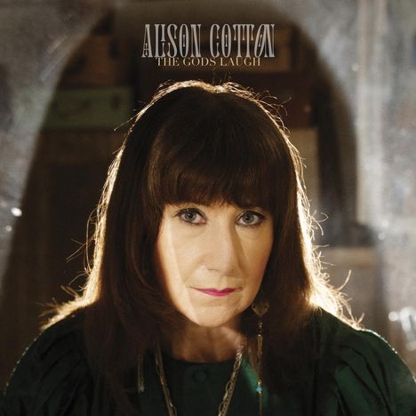 Text: "ALISON COTTON THE GODS LAUGH". Eine Frau mit langen Haaren, ernstem Blick, in warmer Beleuchtung.