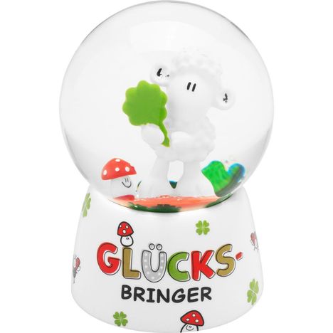 Text: "GLÜCKS-BRINGER". Eine Schneekugel mit Schaf, Kleeblatt und Fliegenpilzen auf einer weißen Basis.