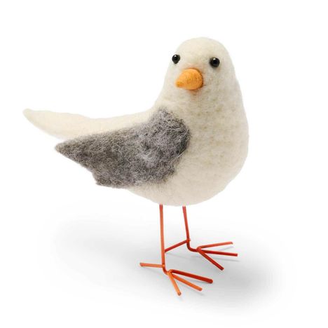Filzvogel mit weißem Körper, grauen Flügeln und orangefarbenem Schnabel, auf dünnen roten Drahtbeinen stehend.