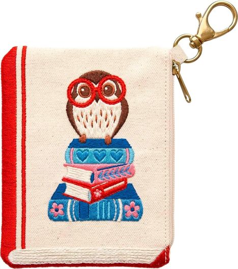 Eine gestickte Eule mit roten Brillen sitzt auf gestapelten Büchern, an einer Tasche mit einem goldfarbenen Haken.