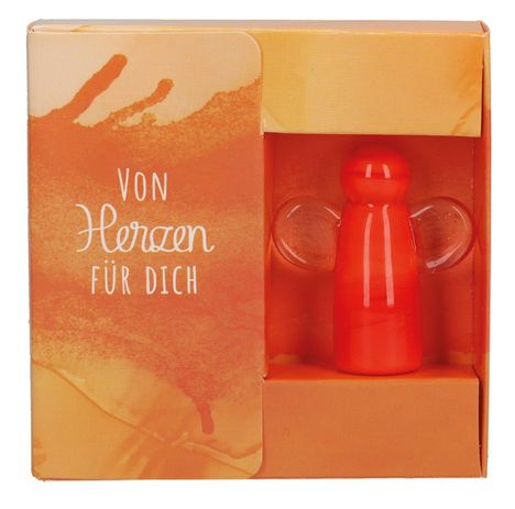 "Von Herzen für dich" steht auf einer orangefarbenen Verpackung mit einer roten, engelsförmigen Figur aus Glas.