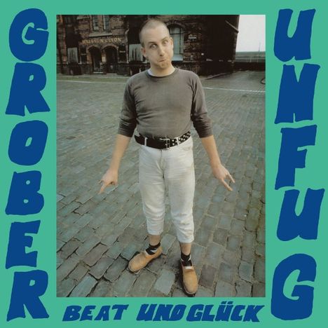 Text: "GROBER UNFUG BEAT UND GLÜCK". Ein Mann steht auf Kopfsteinpflaster, trägt Holzschuhe und blickt schräg nach oben.