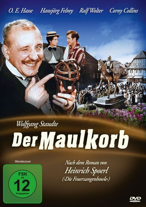 „FSK ab 12 freigegeben“. Ein Mann zeigt auf einen Maulkorb, historische Stadtszene, Reiterstatue, lächelnde Gesichter.