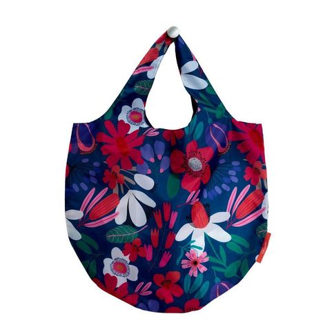 Bunte Tragetasche mit lebhaftem Blumenmuster in Rot, Weiß, Grün und Lila-Tönen auf dunkelblauem Hintergrund.