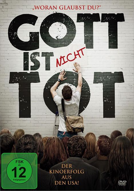 „Woran glaubst du?“ Größerer Text: „Gott ist nicht tot“. Junge Person befestigt Schild. Publikum schaut zu. FSK 12.