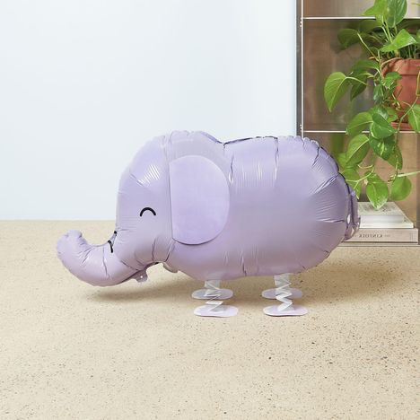 Eine lilafarbene Elefantenballon-Figur mit geschlossenen Augen und einem Lächeln, steht auf einer beigen Oberfläche.