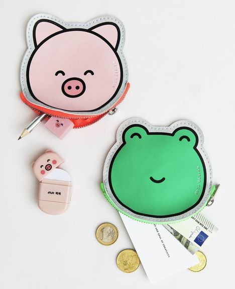 Logo: NDP DESIGN. Zwei runde Taschen: ein rosa Schweinchen, ein grüner Frosch. Umgeben von Münzen, Karten und einem Stift.