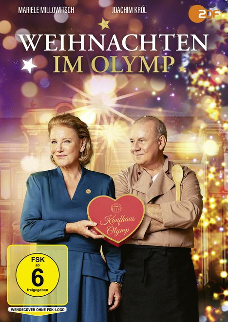 "Weihnachten im Olymp", FSK ab 6. Zwei Personen, Frau in blauem Kleid hält Herz mit "Kaufhaus Olymp". Festliche Beleuchtung.