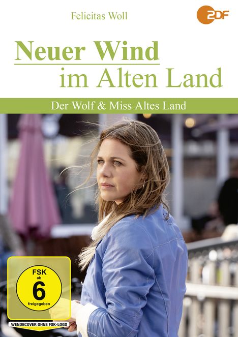 "Neuer Wind im Alten Land: Der Wolf & Miss Altes Land." Frau in blauer Jacke schaut nachdenklich zur Seite.