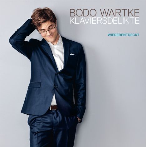 Text: "Bodo Wartke Klaviersdelikte Wiederentdeckt". Ein Mann im Anzug lächelt und greift sich in die Haare.
