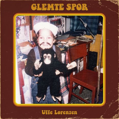Titel "Glemte Spor" und "Uffe Lorenzen". Ein Kind in Verkleidung hält ein Plüschtier, umgeben von einem unordentlichen Zimmer.