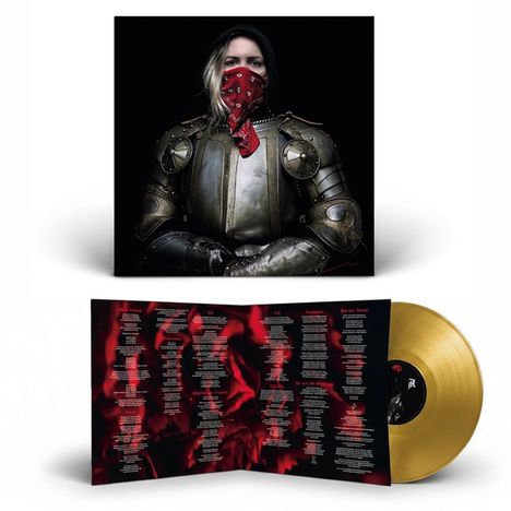 Das Bild zeigt ein Album mit Songtexten in Rot auf schwarzem Hintergrund und eine goldene Schallplatte; darauf eine Person in Rüstung.