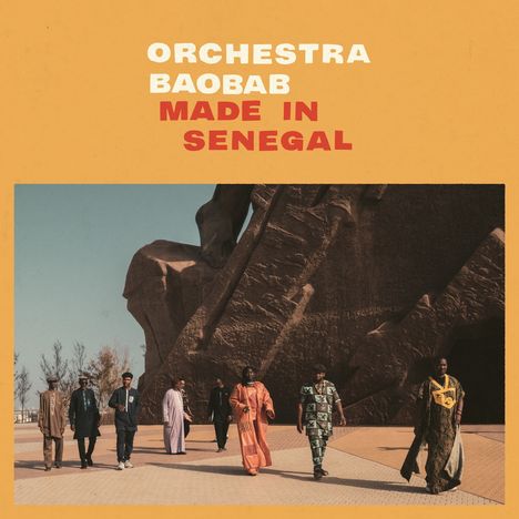 "Orchestra Baobab Made in Senegal" steht oben in großer Schrift. Mehrere Personen gehen vor einer massiven Statue.