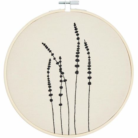 Eine Stickerei mit schwarzen, minimalistischen Pflanzenmotiven auf hellem Stoff, gerahmt in einem Stickrahmen.
