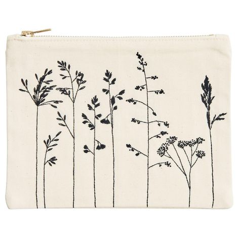 Eine beige Stofftasche mit schwarzem Blumenmuster, zeigt filigrane Pflanzenstängel und Blätter.