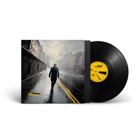 „TIBURSKY COMING HOME“ steht auf einem Schallplattencover. Eine Person geht auf einer nassen Straße im Regen.